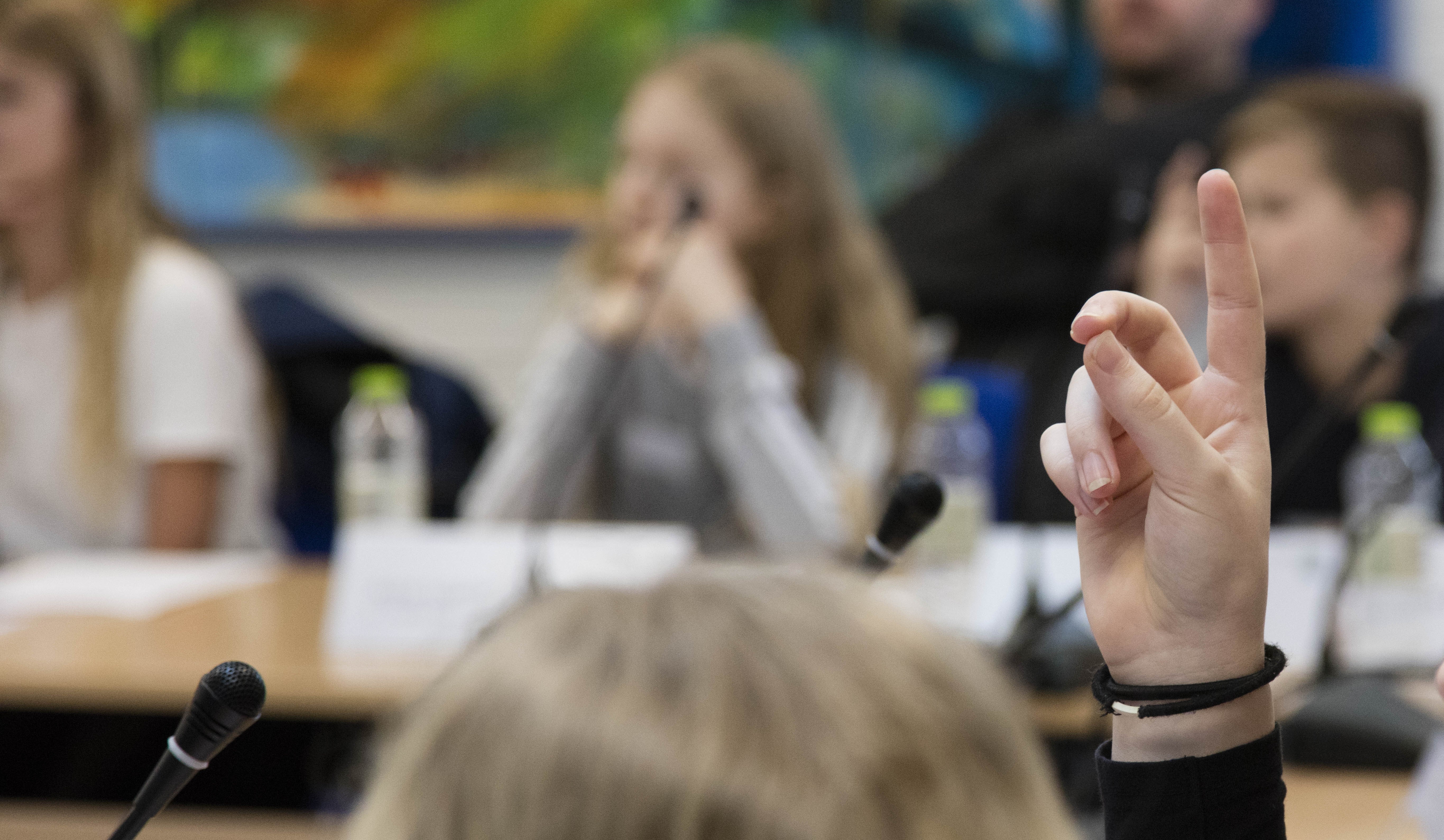 ET barn rækker hånden op foran en mikrofon